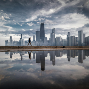 Chicago skyline with its reflection and a girl walking between them