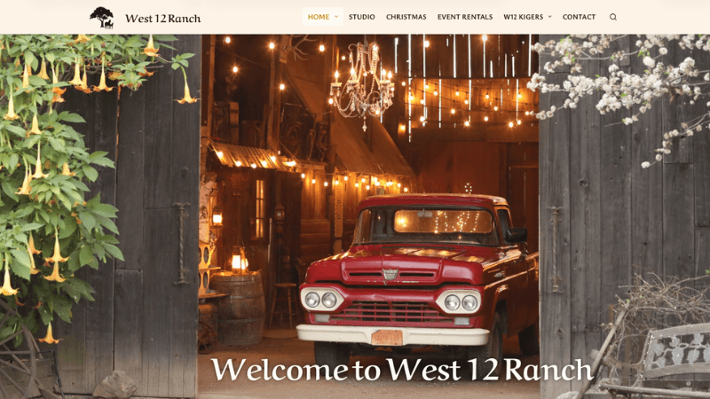 Flowering trees next to an red truck in an open barn lit with string lights and a chandelier